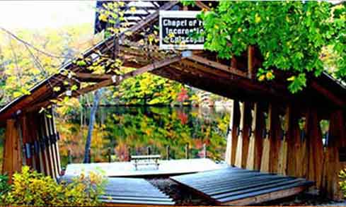 A wooden archway leads to a platform that overlooks a lake.