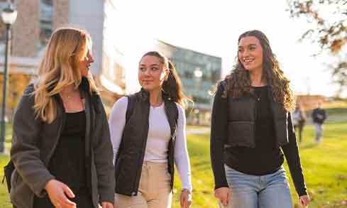 Three students walk outdoors.