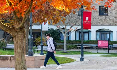 Students walk on stone pathways by banners that read “Fairfield University”.