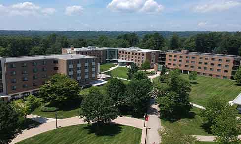 An aerial view of campus with stone paths, green grass, trees, and brick buildings.