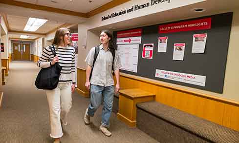 Two students walk together in the hallway of the School of Education and Human Development