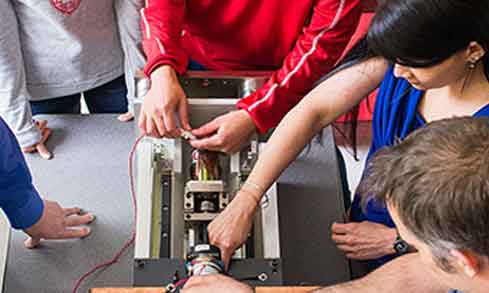 Students working on computer hardware with professors.