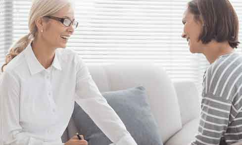 Two women sit across from each other in an office.