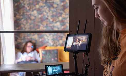 A woman recording a video with a camera, focused and engaged in her content creation process.