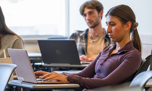 A student takes diligent notes on her laptop during class.