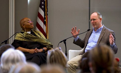 Speakers conversing while seated during a live lecture event.