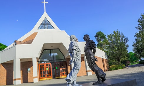 Black and white 'Examen' statue of St. Ignatius facing ('examining') himself, located outside Fairfield's Egan Chapel.