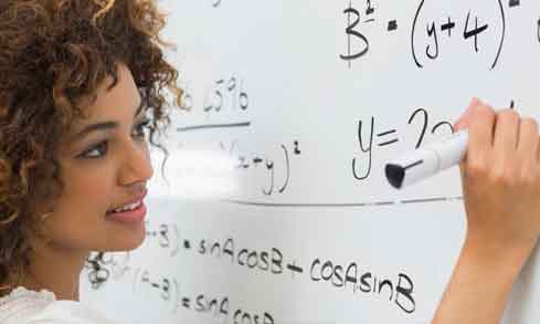 A student writes a math equation on a whiteboard with a black expo marker.