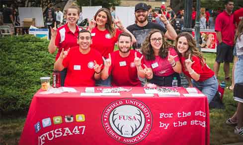 FUSA student pose behind their table at an activities fair.