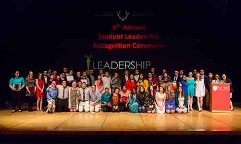 Students pose for a photo on stage during a leadership recognition ceremony