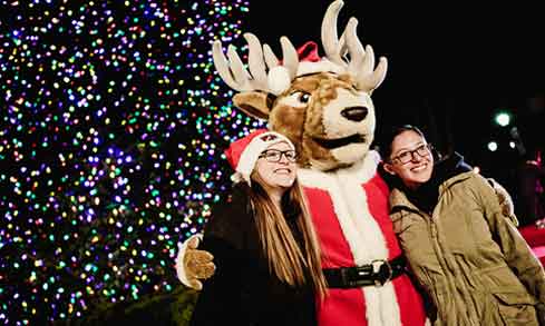 Two students pose with Lucas the Stag at the Christmas Tree Lighting.