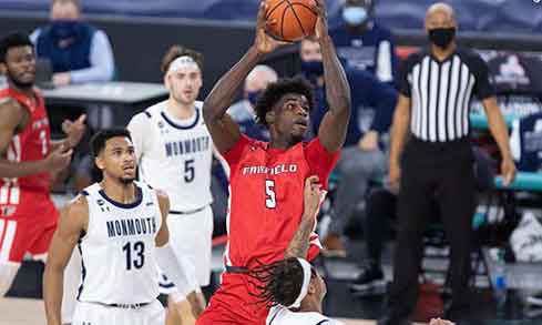 Fairfield basketball player in the air trying to score with Monmouth basketball players surrounding him