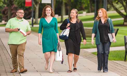 Graduate students walking on campus path talking.