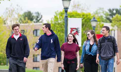 Students talking and walking through campus on a sunny day. 