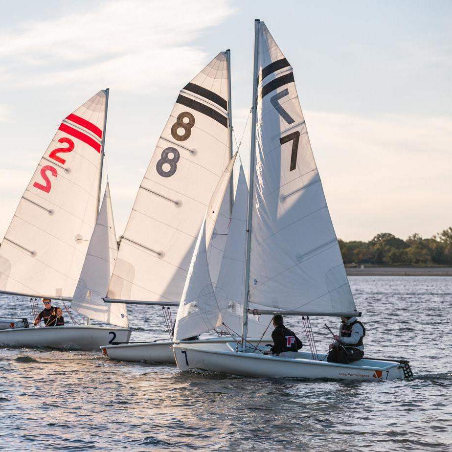 Students ride a sailboat on sunny water.