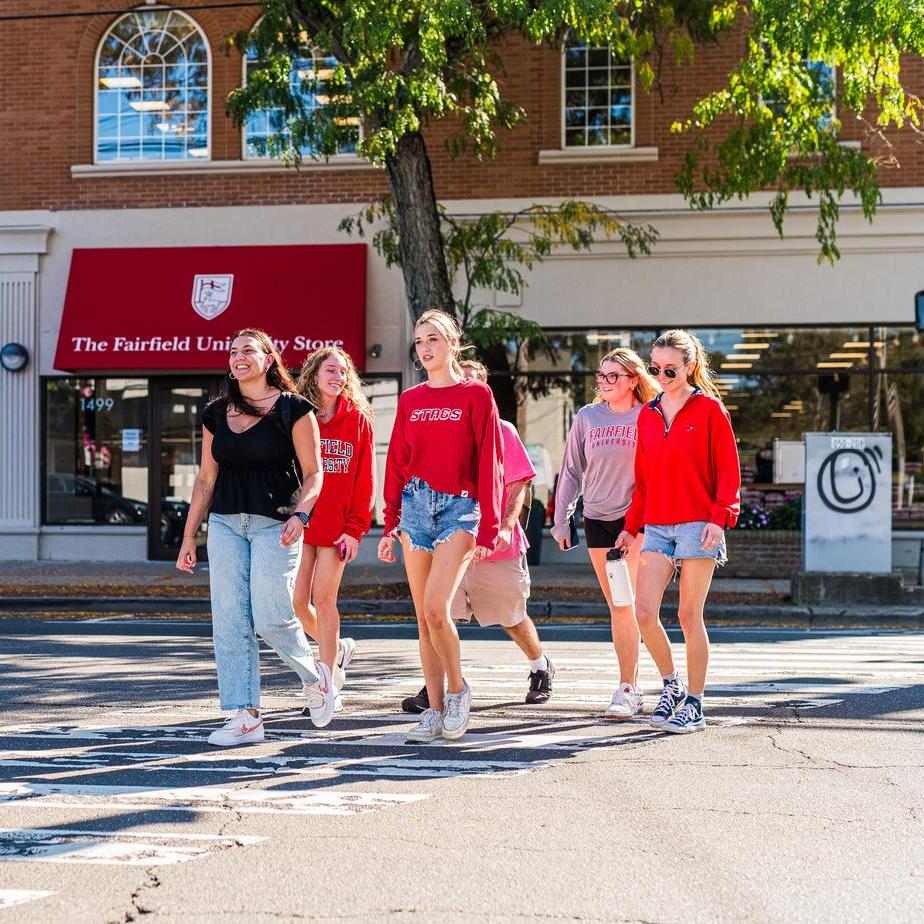 A group of students in Fairfield merch cross the street on a crosswalk.