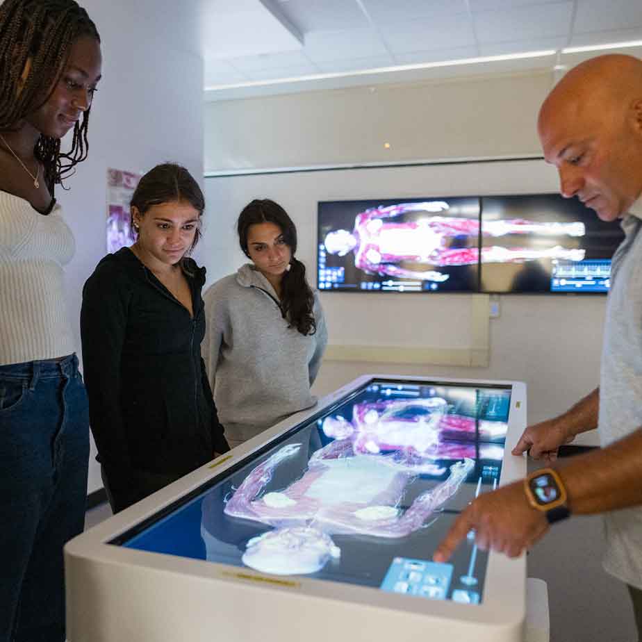 Several people gathered around an interactive display, actively exploring its features and sharing insights in a dynamic environment.