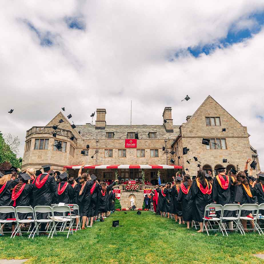 Graduates in black gowns and caps joyfully toss their caps into the air, celebrating their academic achievements.