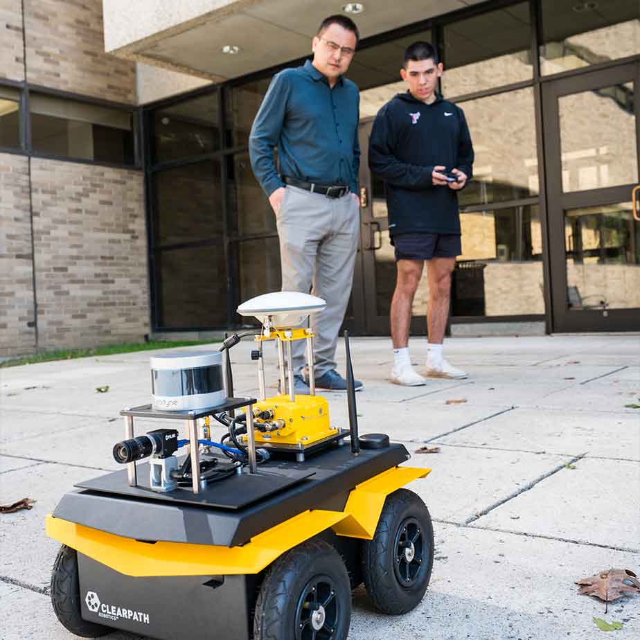 Two men stand beside a robot on the sidewalk, showcasing a blend of human interaction and technology in an urban setting.