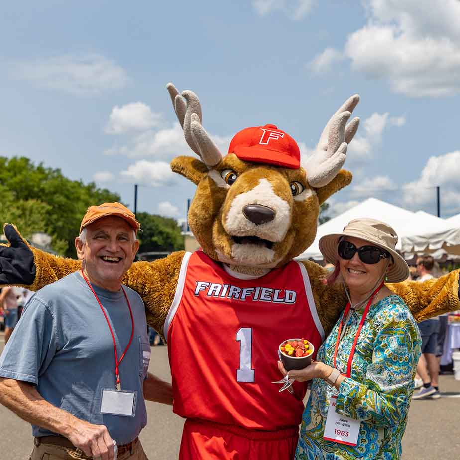 Two individuals pose with a Lucas the Stage at an outdoor event, showcasing a festive atmosphere and community engagement.