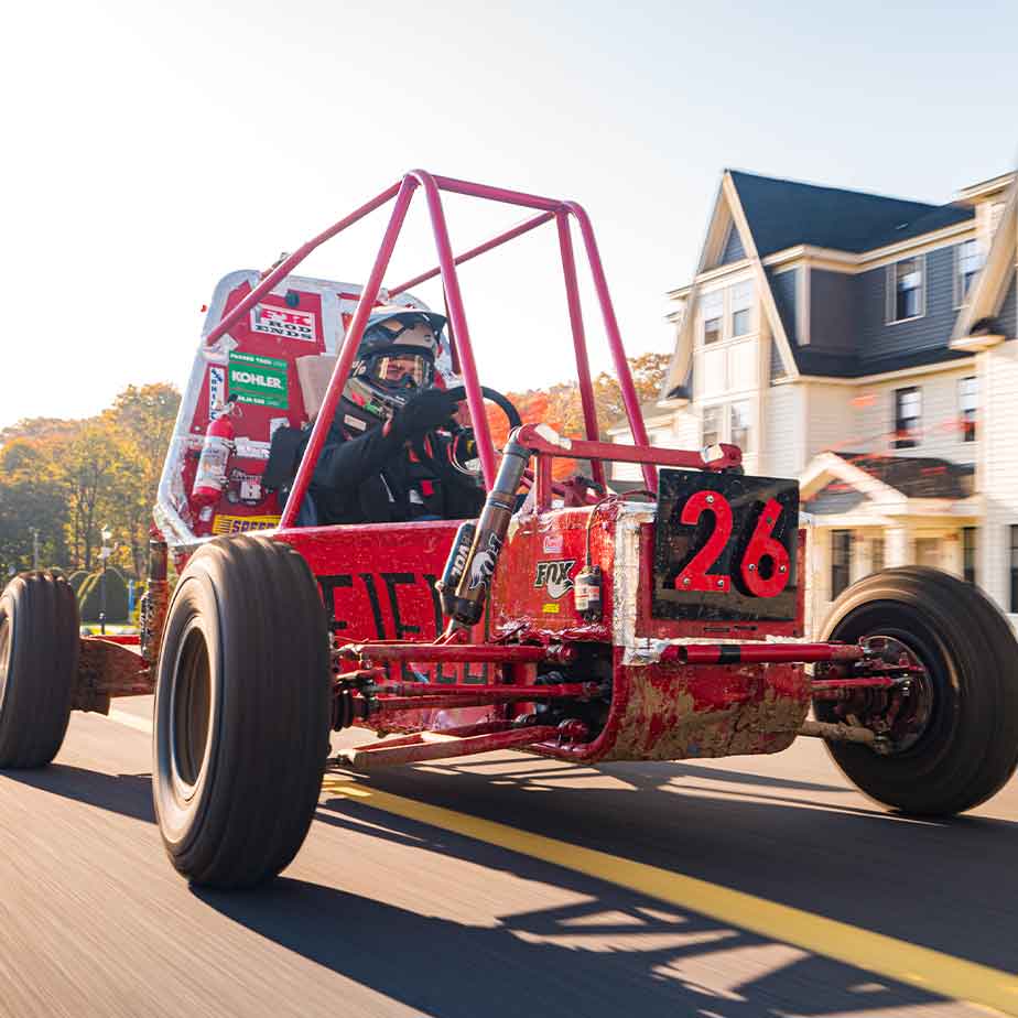 A vibrant red race car speeds down a winding road, showcasing its sleek design and dynamic motion.