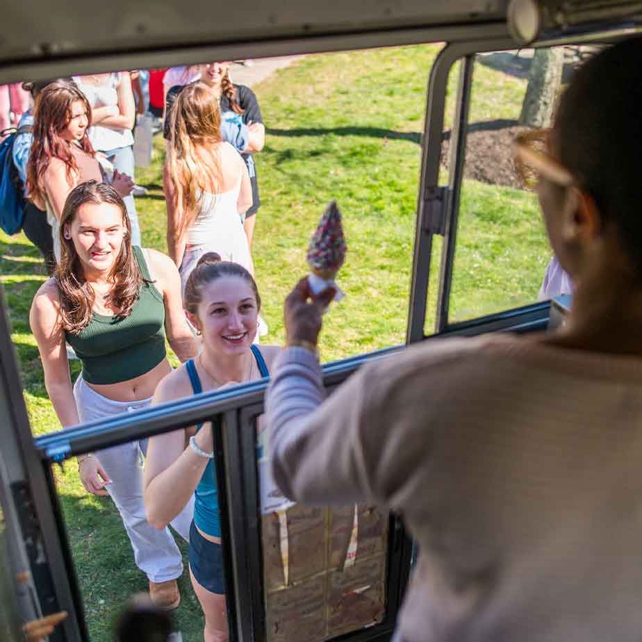 A woman enjoys an ice cream cone while seated inside a bus, capturing a moment of delight during her journey.