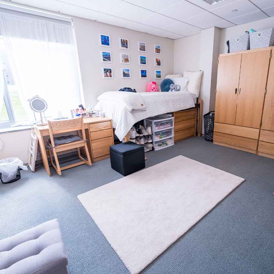 A cozy dorm room featuring a bed, a desk, and a chair, creating a comfortable study and rest environment.