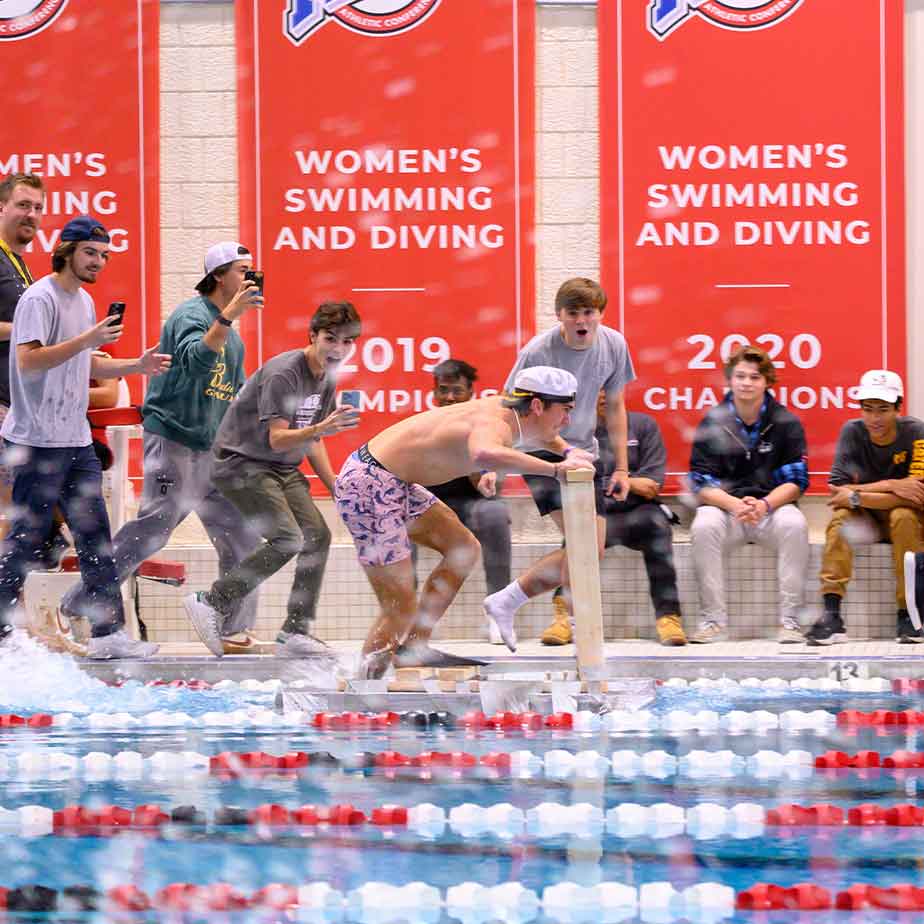 Engineering students compete in the annual walk on water event.  Fans a cheering as a student races his invention across the RecPlex pool.