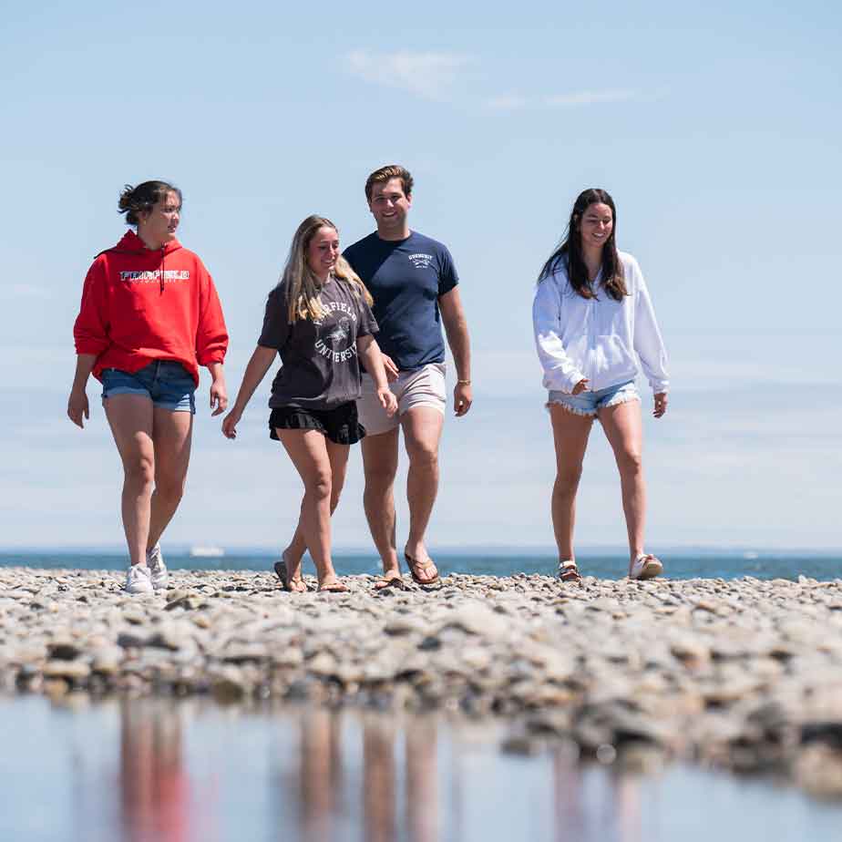 four students walk on the Fairfield beach.