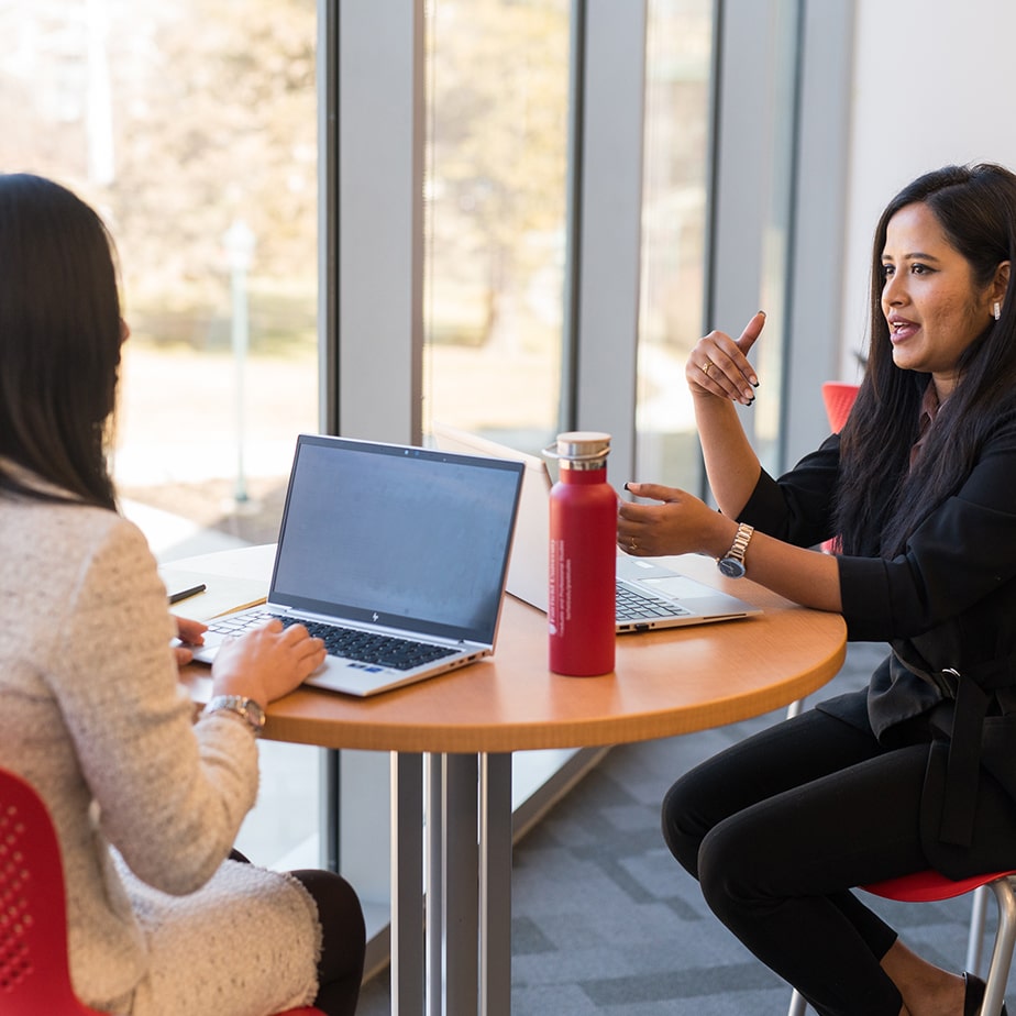 Two students sitting and talking in a university collaboration space.