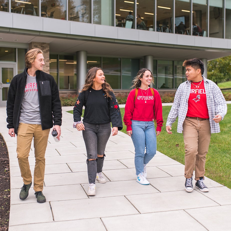 Students walking away from a university building talking and smiling. 