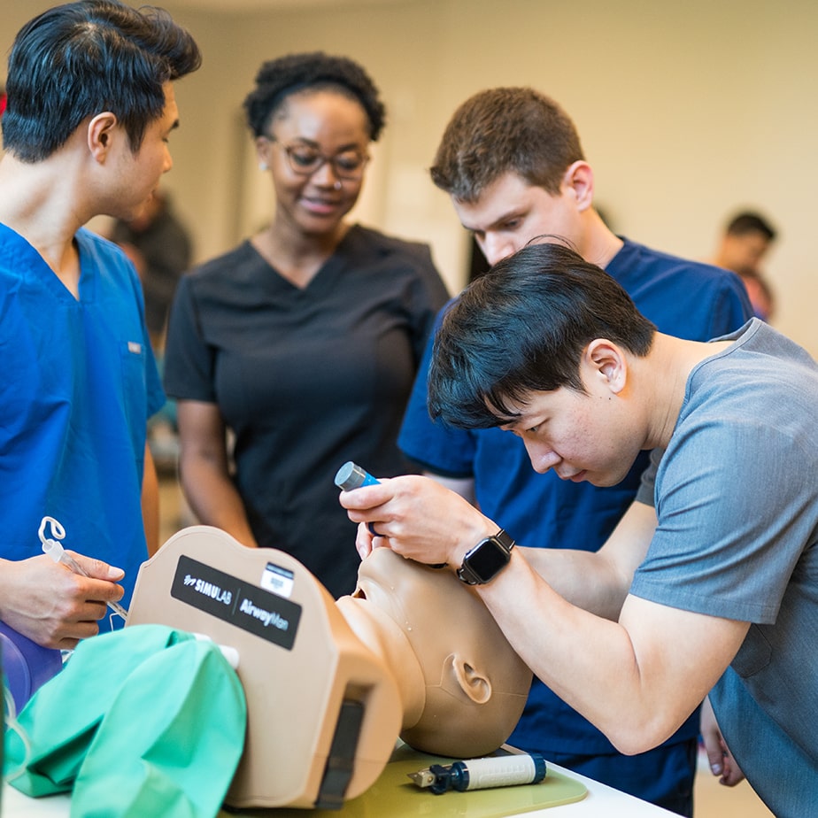 Nursing students testing out anatomically correct, 3D-printed silicone-like tracheas on simulation doll heads.