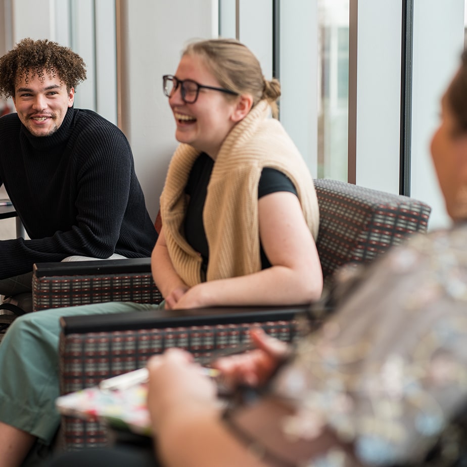 Students sitting and laughing in a university building.