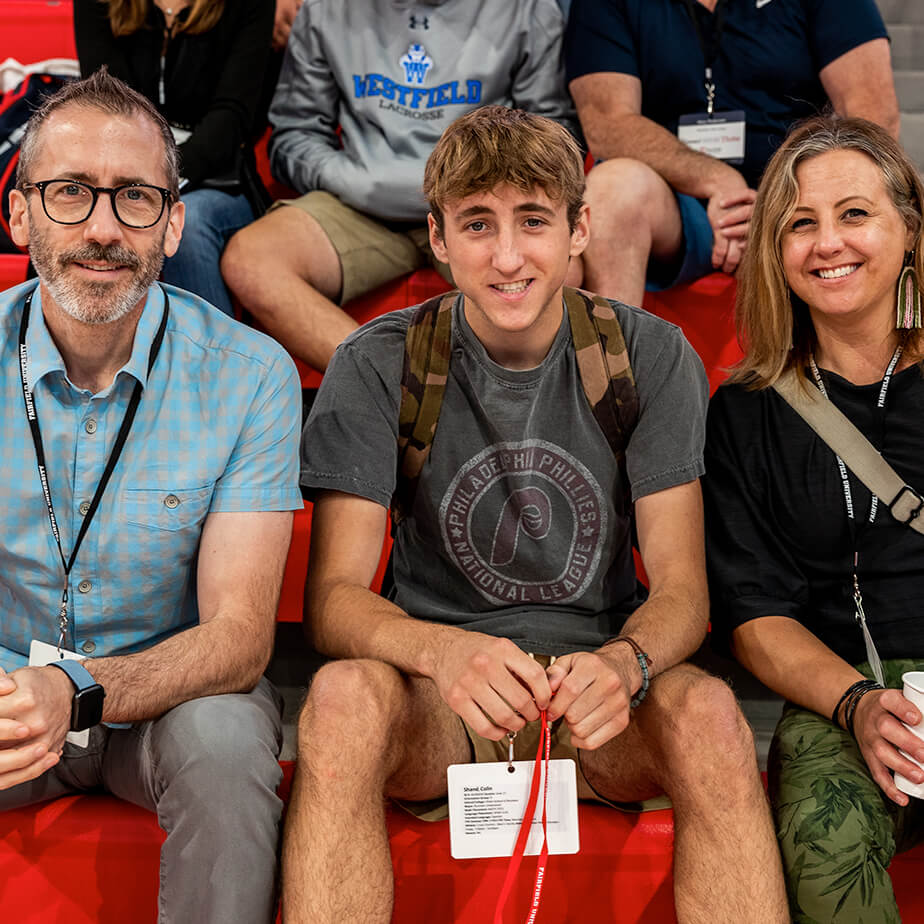 Several people of various backgrounds sitting together on bright red bleachers, creating a lively and social atmosphere.