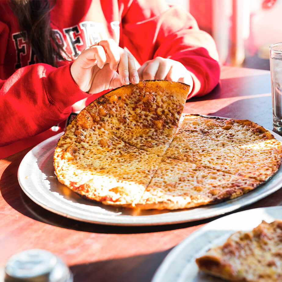 A woman at a table with a pizza and a glass of water in front of her.