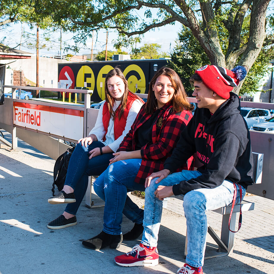 A group of friends relaxing on a bench, surrounded by greenery, as they engage in lively discussion and laughter.