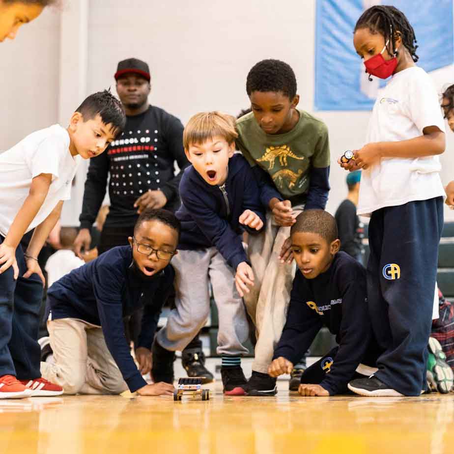 A group of kids play with a toy car.