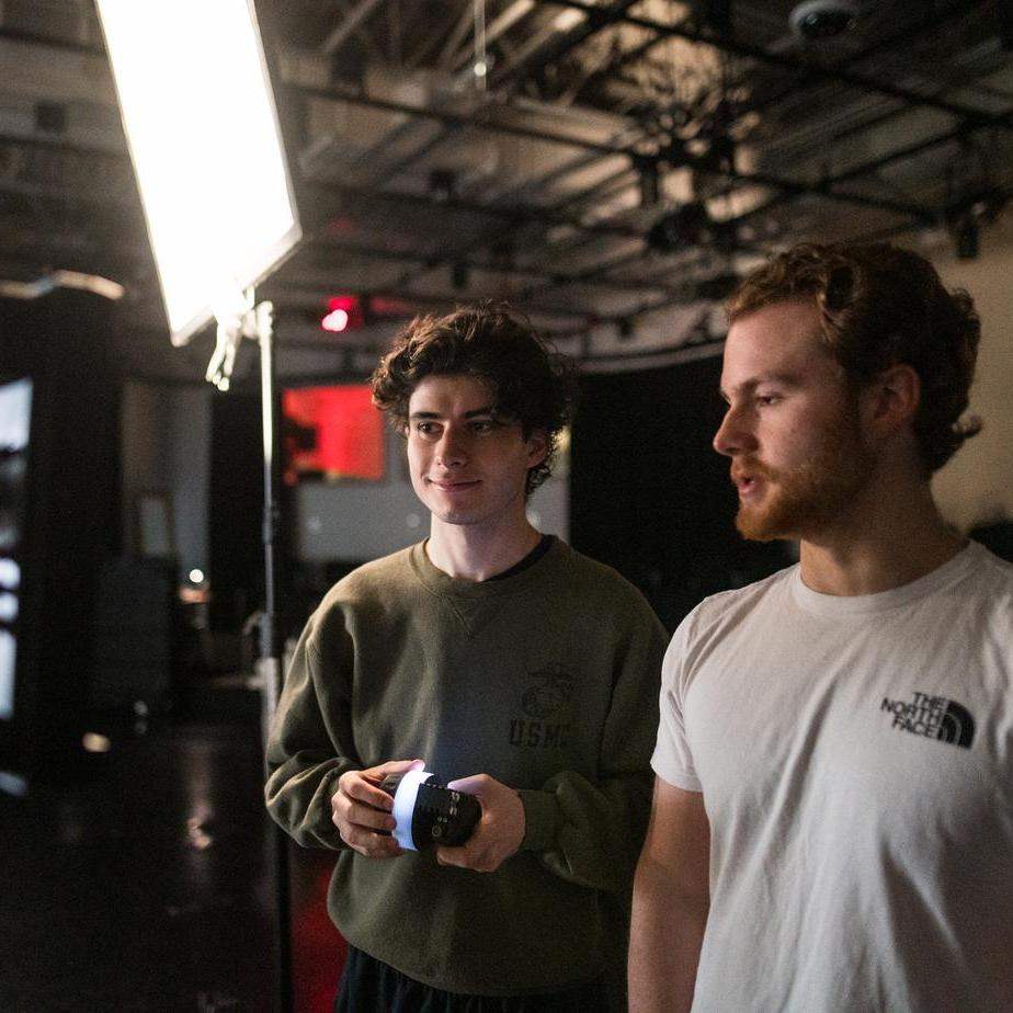 Two student discuss something in a studio for a film class