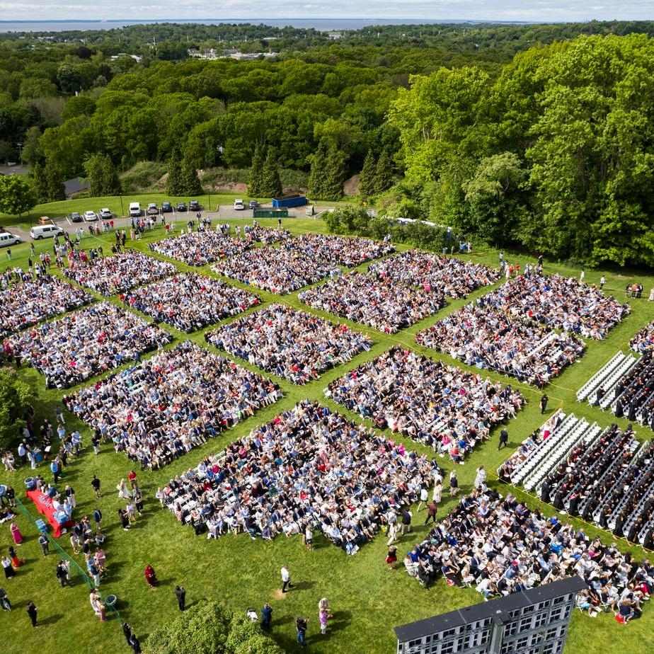 Aerial view of a large crowd celebrating Commencement, showcasing students in caps and gowns gathered in a festive atmosphere.