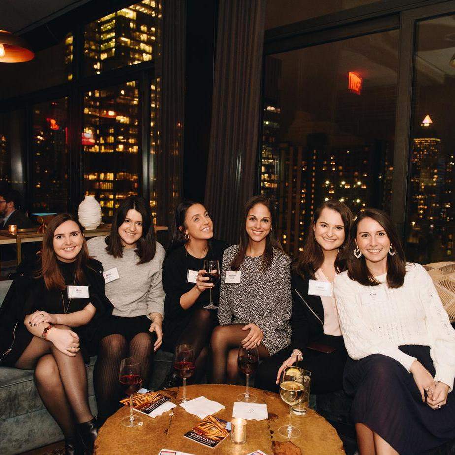 Six women sitting together around a table at an alumni event in New York City.