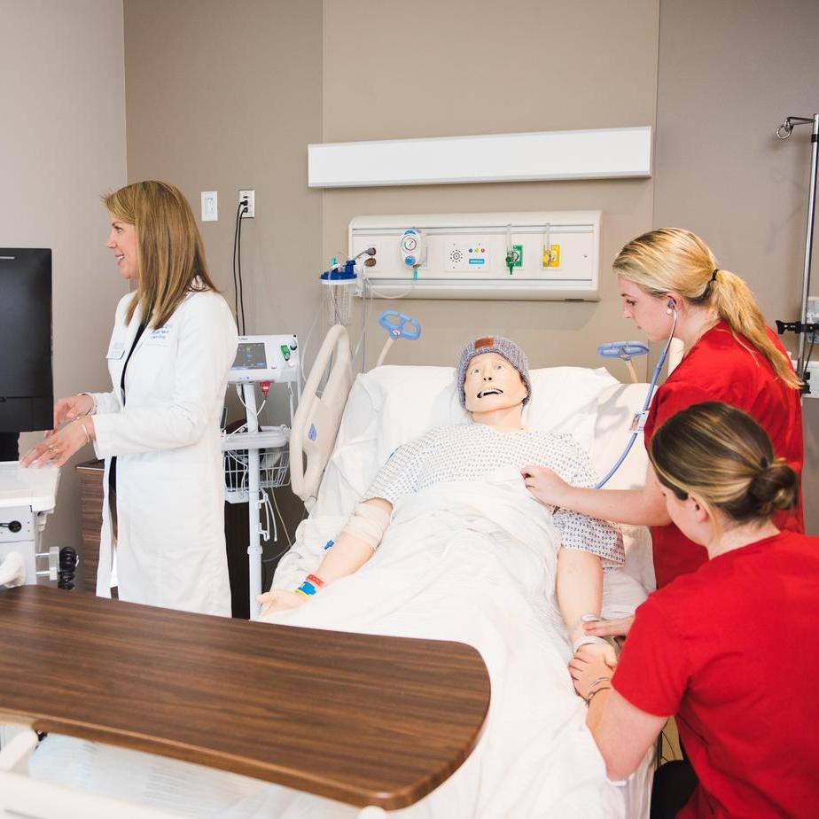 A group of nurses attending to a patient in a hospital room, showcasing teamwork and care in a medical setting.