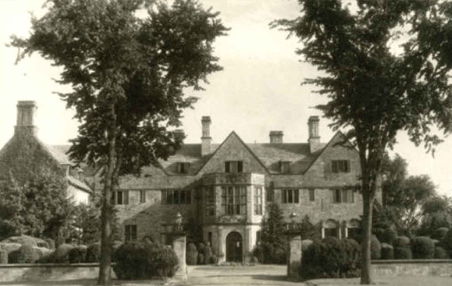 An old black-and-white photograph of the exterior of Bellarmine Hall with two trees.