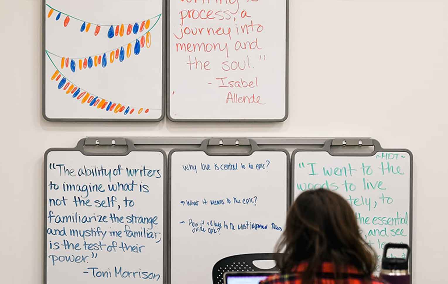 a student sits in front of a wall of portable whiteboards