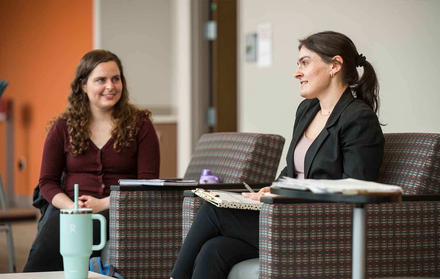 a faculty sit in chairs talking.