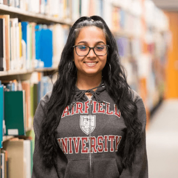 Aliyah Seenauth smiles in front of library books.