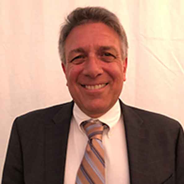 John Iannarone smiles in front of a white background.