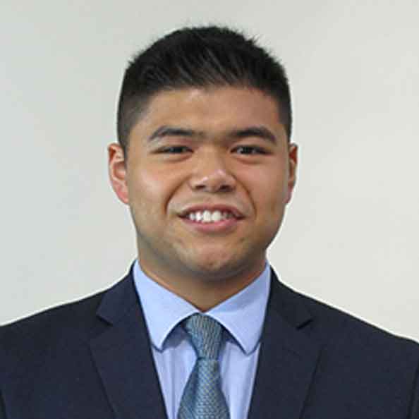 Matthew Marcelo smiles in front of a gray background.