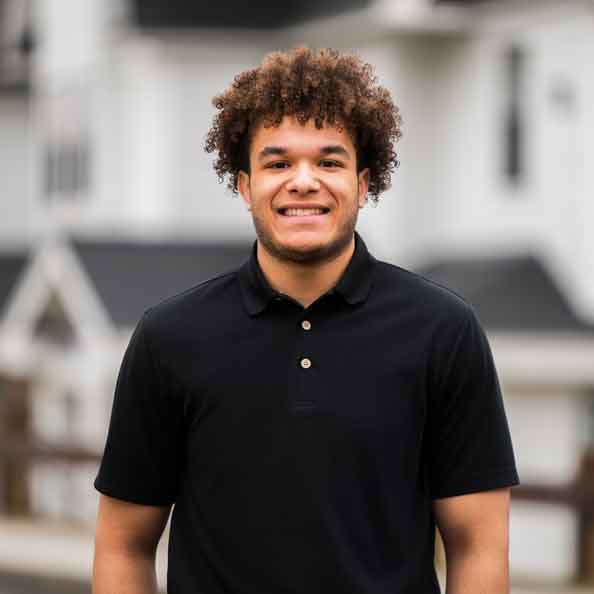 Student posing for photo with townhouses in background. 