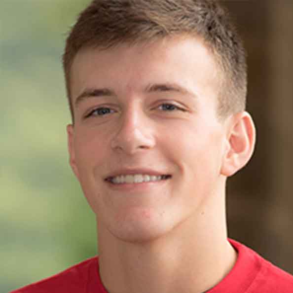 Kyle Klaschka smiles in a red shirt.