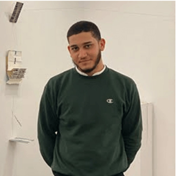 Justin Gomez stands in front of a white wall.